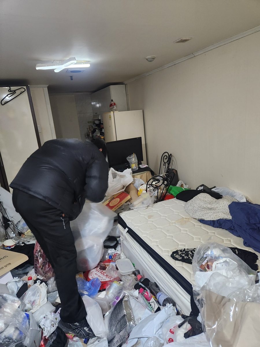 생활쓰레기로 바닥이 매립된 원룸과 작업자